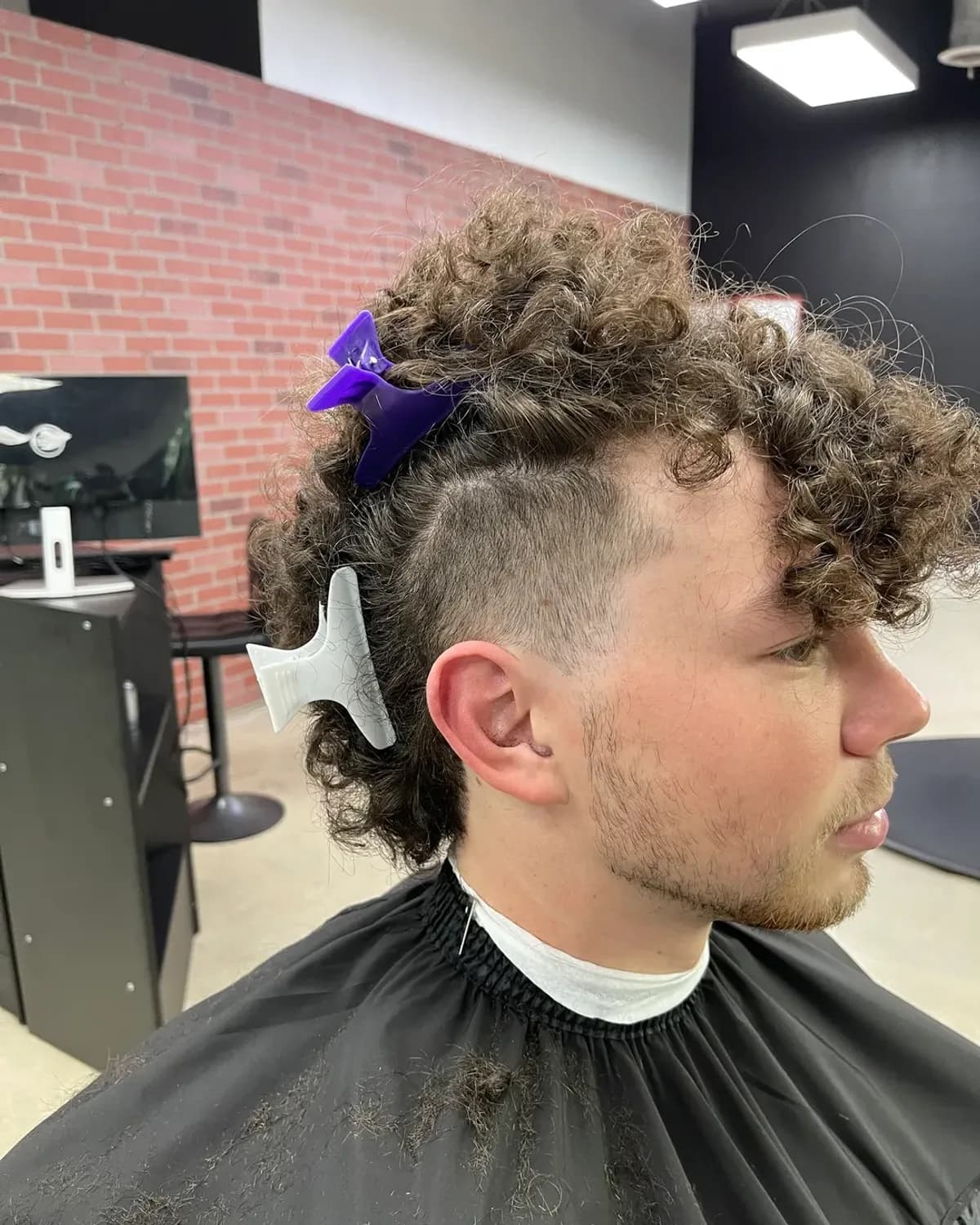 A client caped up in the chair at Grove Batu Barbershop in Coconut Grove
